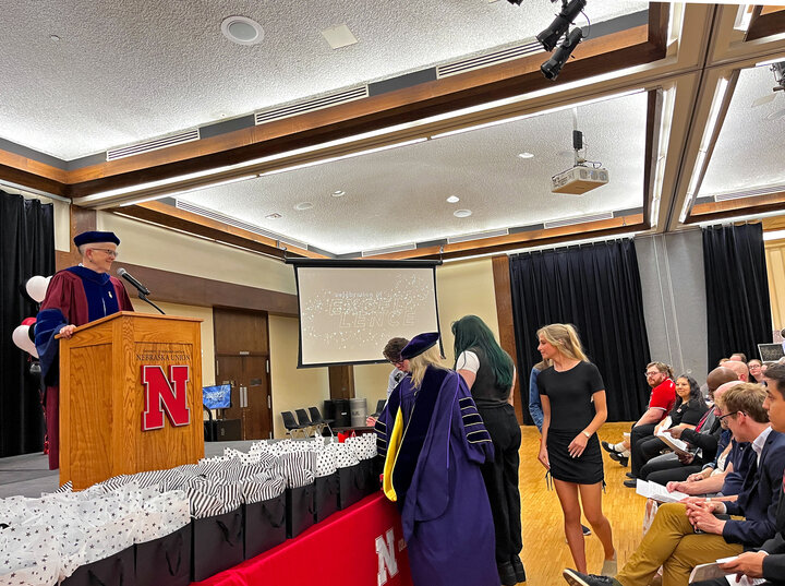 A speaker at a podium announcing the names of inductees at Spring 2024 Celebration of Excellence.