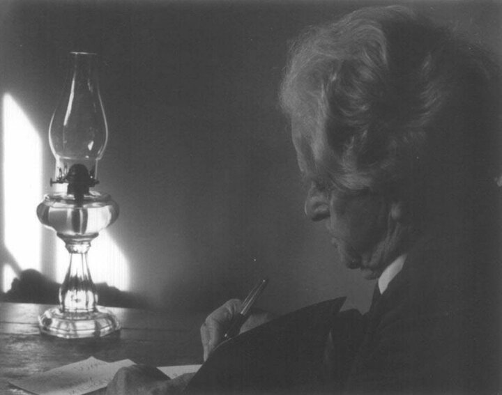 A photo of Neihardt in profile sitting before an oil lamp, writing